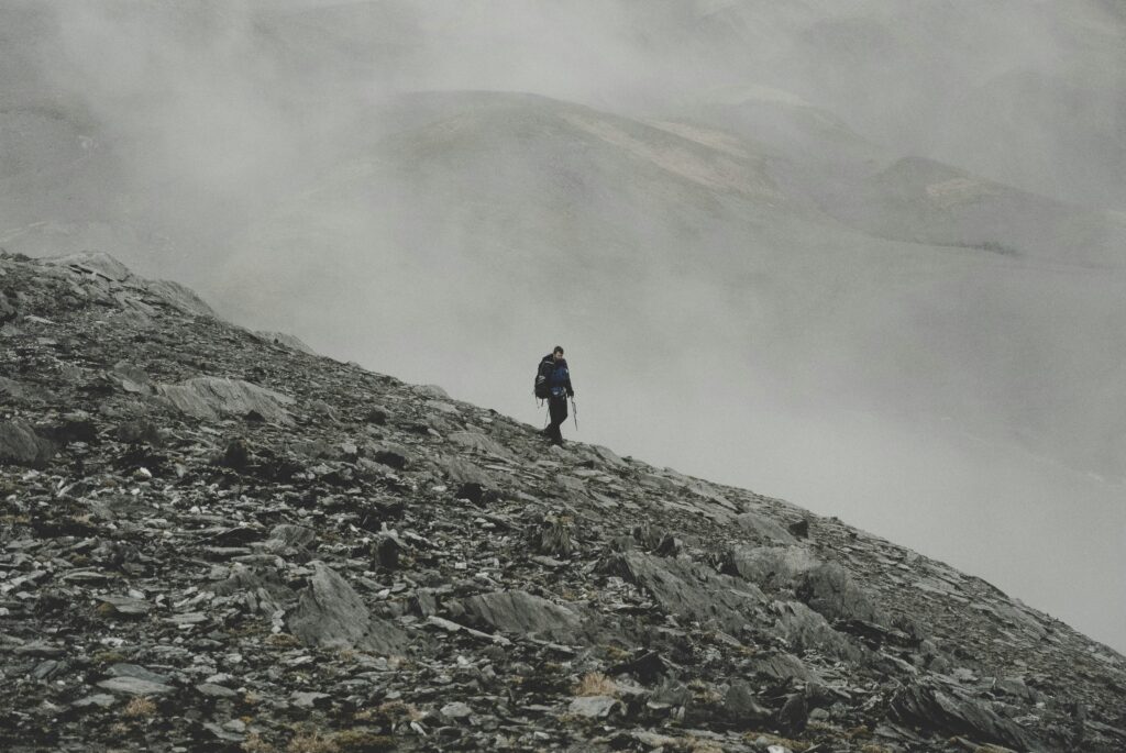  hiker on mountain summit with arms raised symbolizing resilience