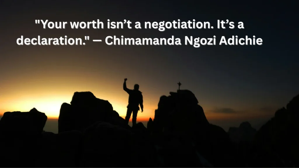 Silhouette of woman with arms raised on a mountaintop at daw
