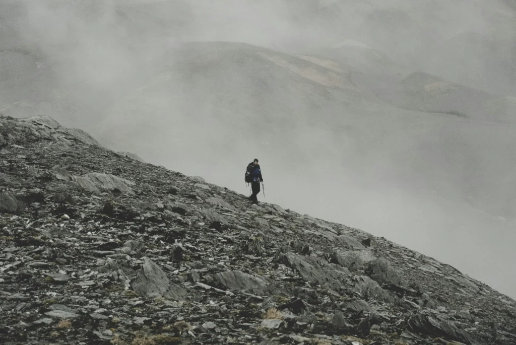  hiker on mountain summit with arms raised symbolizing resilience