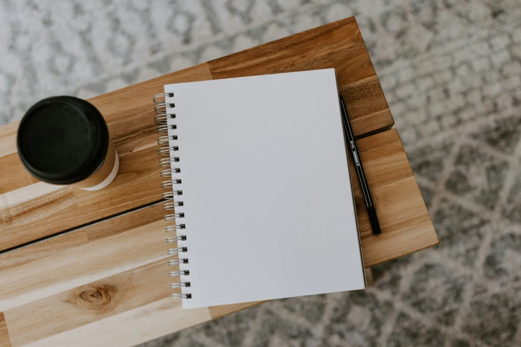  flat‑lay of notebook with ‘Joy’ handwritten and coffee cup for inspiration